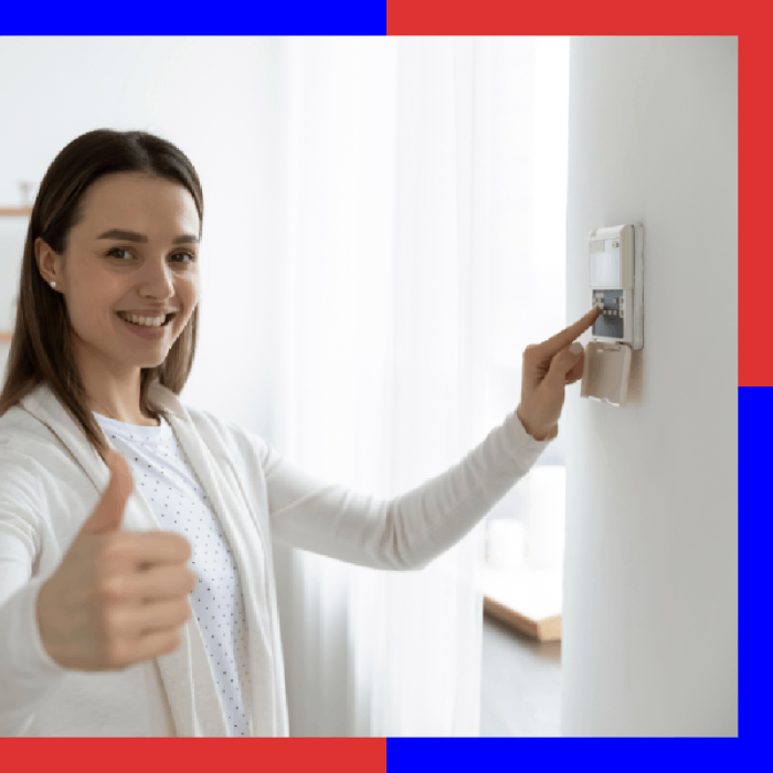 Mujer sonriente presionando el botón de un panel de control instalado en la pared